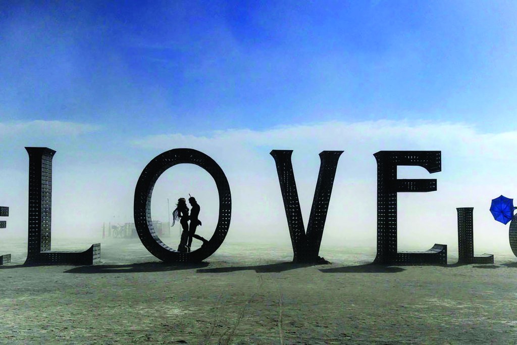 In this Aug. 30, 2014 photo, a couple stands inside a love sculpture at Burning Man on the Black Rock Desert of Gerlach, Nev. The #MeToo movement is making its way to Burning Man which begins Aug. 26-Sept. 3, 2018. Organizers are reminding attendees that just because the counterculture festival in the Nevada desert is known for occasional nudity and kinky landmarks like the "Orgy Dome," it doesn't mean it’s a free-for-all when it comes to touching or non-consensual sex. (Andy Barron/The Reno Gazette-Journal via AP)